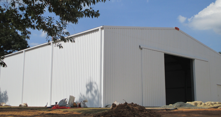 Exterior of a white Frisomat metal hall with large door.
